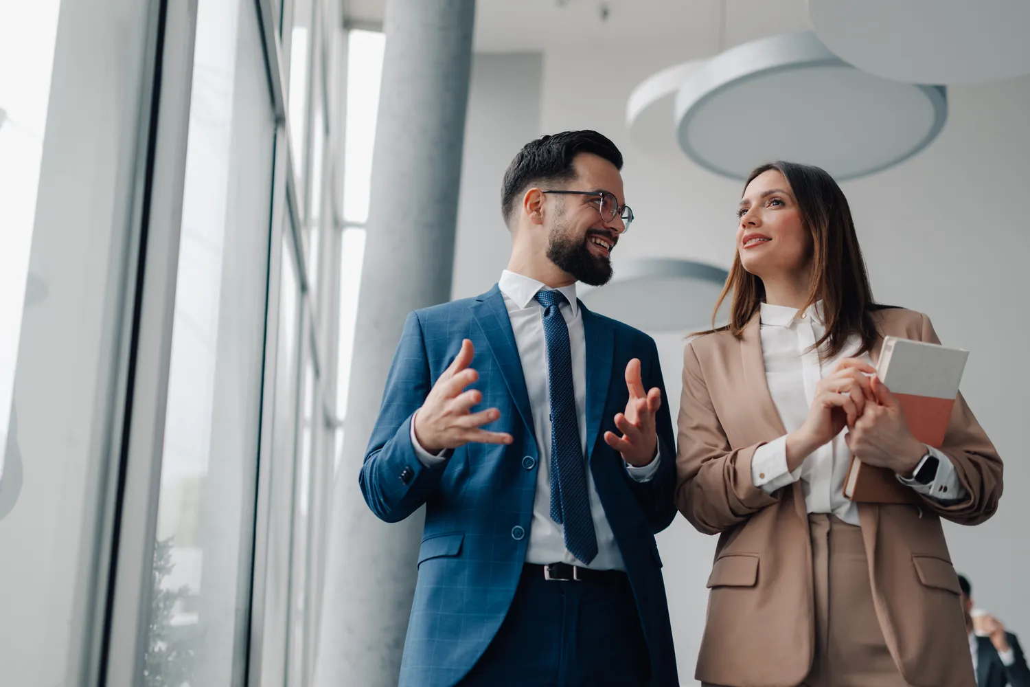CMM - business consulting - Businesspeople discussing work while walking in office hallway